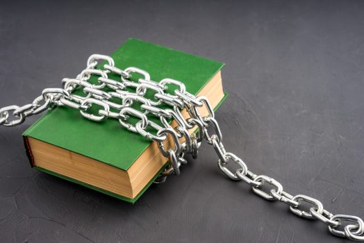 a large green book chained on a gray background. the book is censored
