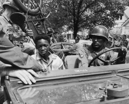 Desegregation 1957: Caucasian National Guardsmen give an African-American student and his bicycle a lift to school while enforcing desegregation at Central High School in Little Rock, Arkansas. A cameraman and a crowd watch from the sidewalk. (Photo by Paul Slade/Hulton Archive/Getty Images)