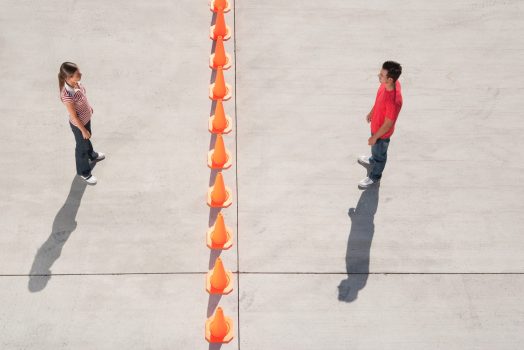 Man and woman on either side of row of traffic cones looking back