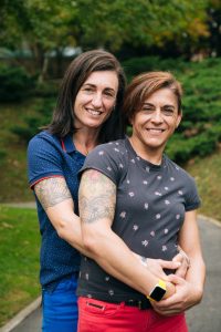 Portrait of a middle aged lesbian couple hugging outdoor Portrait of a happy middle aged lesbian couple hugging and looking to camera in a park