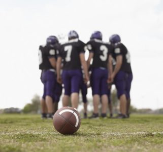Teenage boys (16-18), football players in huddle on field