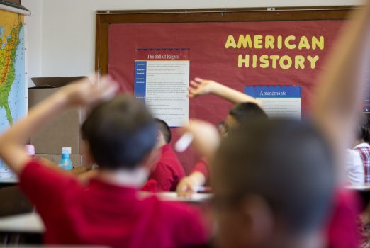 Students have their arms raised during an American history class.