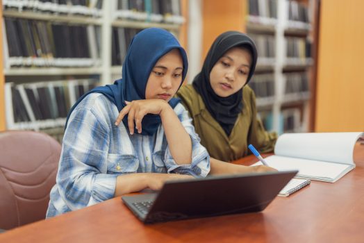 Two Muslim student using laptop doing their paperwork in a library