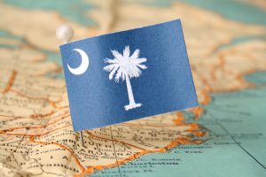 South Carolina flag over more that sixty years old map pointing Columbia city. Shallow depth of field