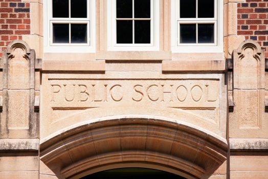 yellow brick and concrete building with public school etched in arch above the door