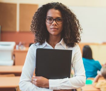 Portrait of mixed race teacher in class standing serious during exam