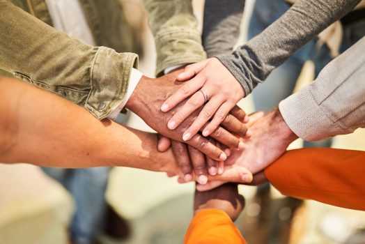 A midsection of businesspeople putting hands together Cropped shot of multi-ethnic group of business people with stacked hands showing unity and teamwork. Unrecognizable business people stacking hands in modern office