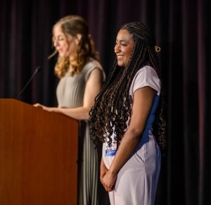 Two women standing beside a podium 