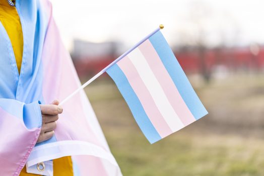 Transgender rights protest Transgender covered with the transgender flag and holding a flag in the hand for defending her rights