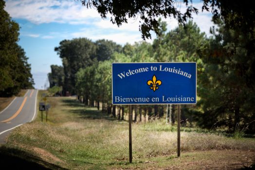 State Line Sign Saying Welcome to Louisiana Remote location state line from Texas to Louisiana on a two lane highway with a sign welcoming travelers into the state of Louisiana. The sign also has the French version, Bienvenue in Louisiane.